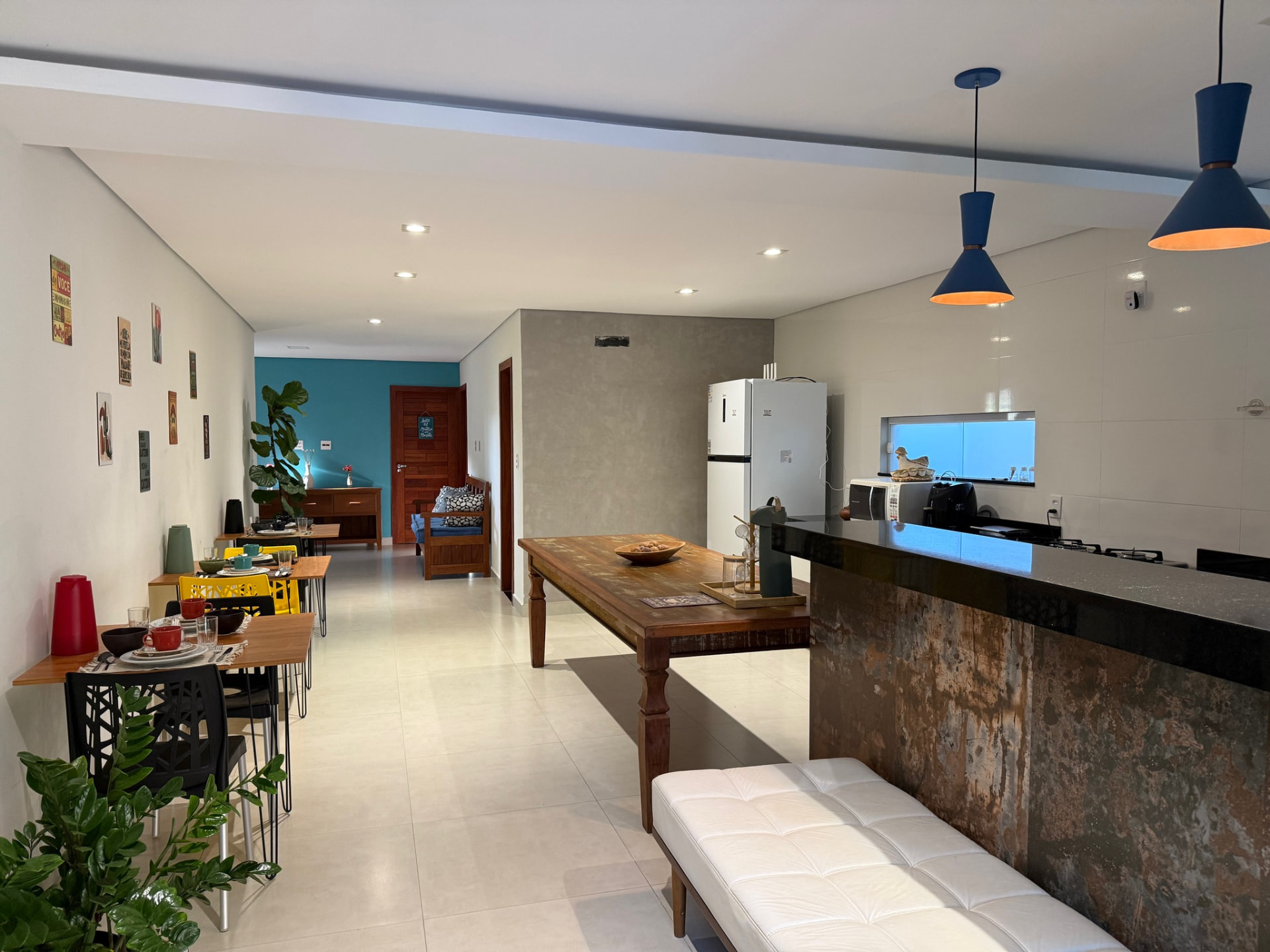 Sala ampla com mesas de café da manhã, cozinha e área de convivência